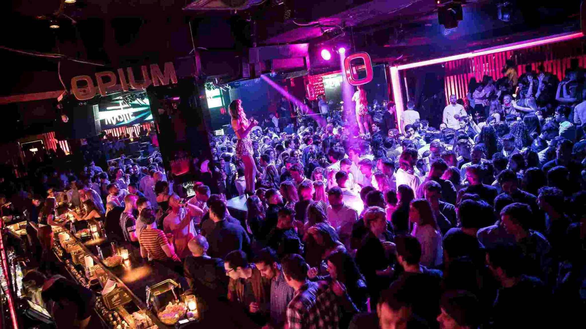Mejores discotecas de Barcelona: Ambiente nocturno en Opium Barcelona con público bailando y luces de neón en la pista de baile.