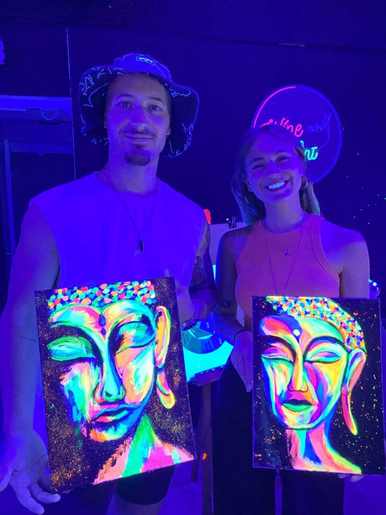 Pareja en taller Wine and Art con cuadros Buddha Glow flúor